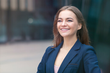 Portrait of beautiful confident business woman outdoors office. Attractive young happy girl in suit, jacket smiling. Successful positive lady look at distance, thinking of future, career. Good news