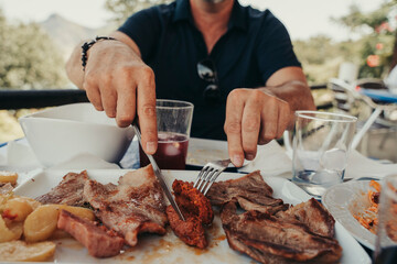 Adult man cutting meat in a restaurant