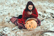 witch grieves over a Halloween carved pumpkin sitting in the snow