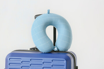 Travel pillow and suitcase on white background