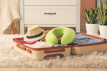 Poster - Travel pillow and open suitcase on floor in room