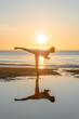 Silhouette of woman practicing the warrior III yoga on the beach at morning sunset scene. 