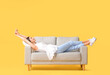 © Pixel-Shot - Young woman relaxing on sofa against color background