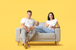 © Pixel-Shot - Young couple relaxing on sofa against color background