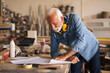 © Jelena - Senior joiner carefully analyzing project blueprint