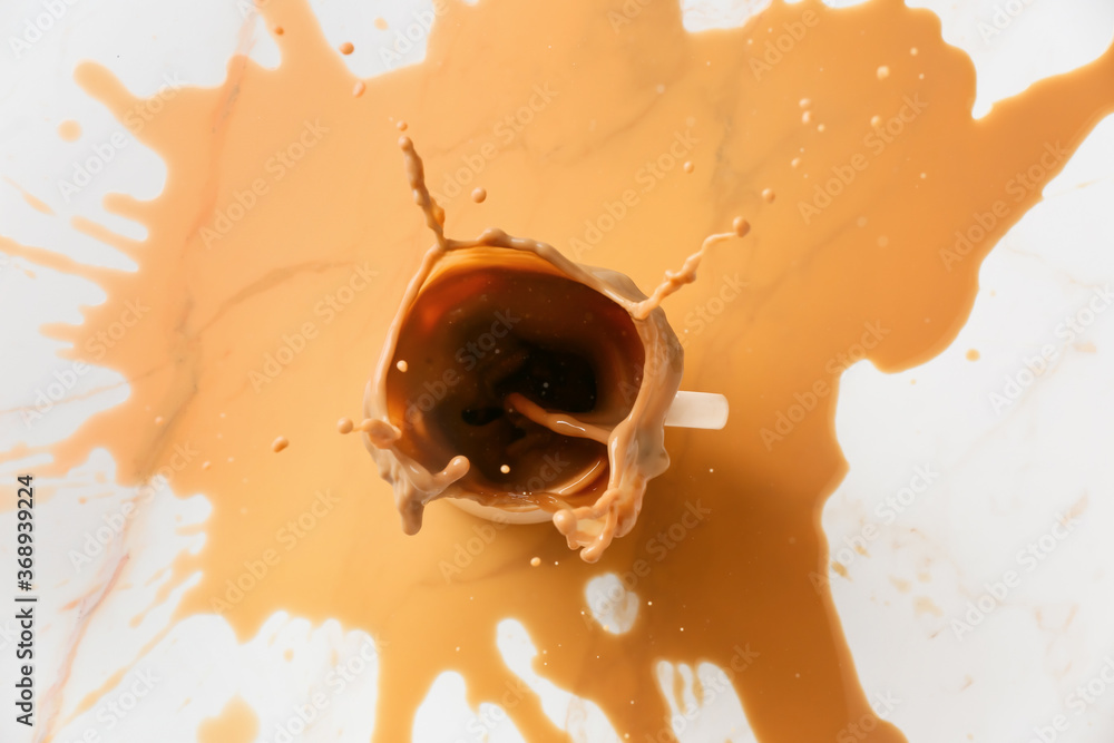 Cup of hot coffee with splash on table