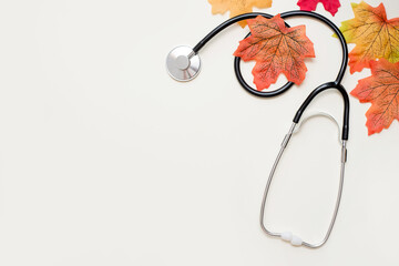 stethoscope with yellow autumn leaves on light background with copy space