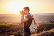 © Seleznov_Molchanova - Man photographer with backpack and camera taking photo of sunset mountains