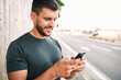 © Astarot - Young man with smart phone texting outdoors in the city