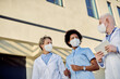 © Drazen - Below view of healthcare workers wearing protective face mask while communicating outdoors.