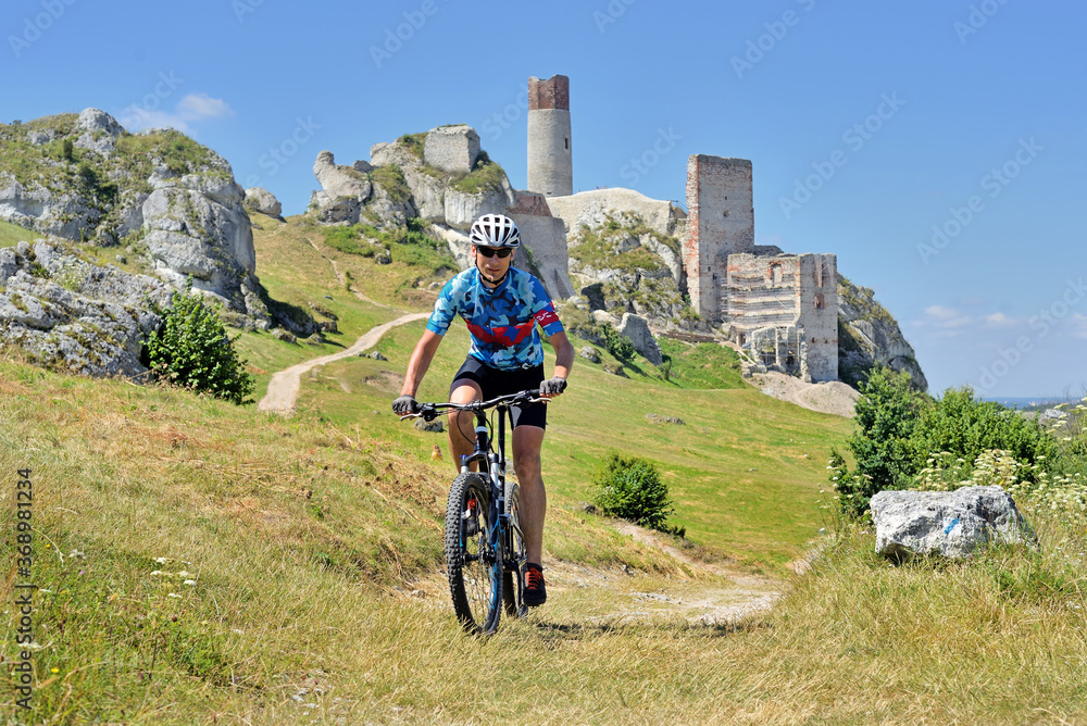 A man on a mountain bike on the hill of Olsztyn Castle. Poland. - obrazy, fototapety, plakaty 