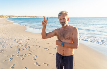 Mature happy active and healthy senior adult having fun on the beach enjoying retirement