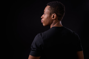 Young handsome African man against black background