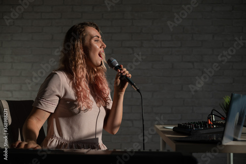 Cuadros en Lienzo A young European woman sings into a microphone and accompanies on an electronic piano