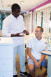 © JackF - Teenage boy looking for stylish glasses with qualified African-American optician in optical shop