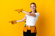 Young electrician woman isolated on yellow background pointing finger to the side and presenting a product