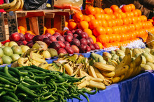 Fruit Stand In A Street Market With Banana, Orange, Apples, Chilli Pepper Wood Box And Blue Plastic Fabric