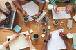 © Seventyfour - Top view close up of multi-ethnic group of people working together at cluttered wooden table with coffee cups, mugs and stationary items, teamworking or studying concept, copy space