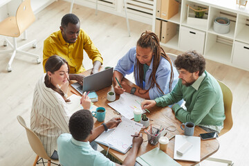 Wall Mural - High angle view at contemporary creative team working together at cluttered table with mugs and stationary items, teamworking or studying concept, copy space