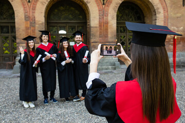 Wall Mural - Young group of graduation students take photo on the phone at campus after ceremony