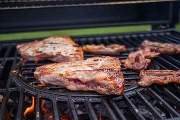 Home barbecue with charcoal in the backyard grilling steaks and other meats for carnivore diet.