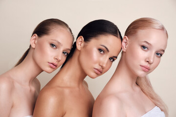  Beauty. A group of diverse portrait models. Girls posing on a beige background. Tender girls standing together and looking at camera