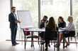 © fizkes - Businessman in suit standing near flip chart in front of interested collective provide information do overview sales result, make presentation for investors, plan common project, coaching work concept