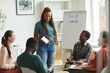 © Seventyfour - Multi-ethnic group of people sitting in circle while discussing business project in office, focus on smiling African-American woman talking to colleagues, copy space