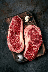 Canvas Print - Two raw new York steaks on a chopping Board with seasonings and garlic. Wagyu meat for grilling, top view