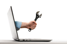 The Human Hand With  Black Wrench Stick Out Of A Laptop Screen. Concept Of Technical Support. Isolated On White.