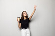 © dianagrytsku - Young woman waving hand while walking and holding cup with coffee isolated over gray background
