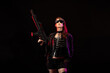 © Warpedgalerie - Young woman dressed in a studded leather jacket, a pair of cyberpunk glasses, holding an assault rifle in her hands