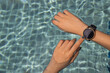 © num - Close up of female using hands with the smart watch at the pool. Healthy lifestyle concept.