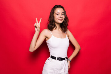 Cheery stylish girl wearing hat showing peace gesture isolated over pink background