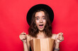 © dianagrytsku - Portrait of a curious young woman in summer hat looking inside shopping bags isolated over red background