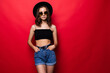 © dianagrytsku - Portrait of woman wearing in floppy hat and sunglasses isolated over red background