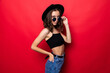 © dianagrytsku - Young pretty woman in floppy hat and sunglasses standing isolated on red background