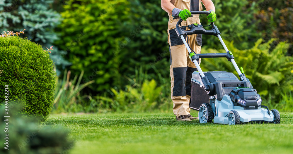 Gardener Trimming Grass Lawn Using Electric Cordless Mower