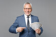 Smiiling elderly gray-haired business man in blue suit shirt tie isolated on grey background. Achievement career wealth business concept. Point index finger on fan of cash money in dollar banknotes.