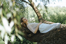 A Young Girl Lies On A Tree Branch