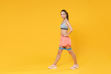 Wall Mural - Full length portrait of young fitness sporty woman girl in sportswear working out isolated on yellow background. Workout sport motivation lifestyle concept. Doing exercise for legs with fitness gums.