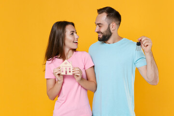 Canvas Print - Smiling young couple friends guy girl in blue pink t-shirts posing isolated on yellow background studio. People lifestyle concept. Mock up copy space. Hold house bunch of keys, looking at each other.