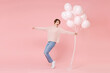 © ViDi Studio - Full length portrait of excited young woman girl in casual sweater isolated on pink background. Birthday holiday party concept. Celebrating hold air balloons dancing standing on toes spreading hands.