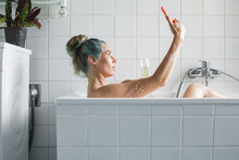 Blue Haired Woman Taking A Selfie In A Bathtub
