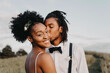 © Chelsea Victoria/Stocksy - A beautiful young black bride and groom posing for portraits in a meadow on their wedding day