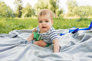 Cute caucasian baby boy n a striped T-shirt. picnic in the summer park.