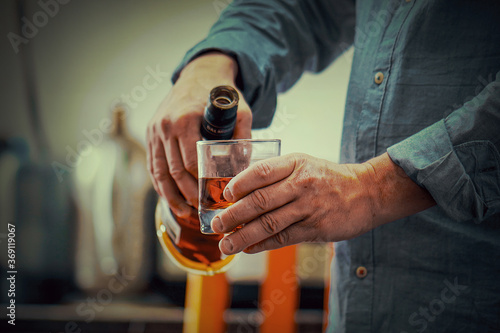 Cuadros en Lienzo Hands of elderly caucasian man with bottle of whiskey on the kitchen
