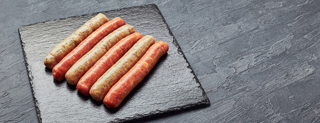 Wall Mural - Raw butchers sausages on slate. Overhead view