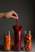 Anonymous Female Hand Reaching For Halloween Candy In Glass Jars.