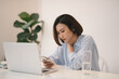 © Maki Company Limited/Stocksy - Thinking asian woman using a mobile phone and laptop